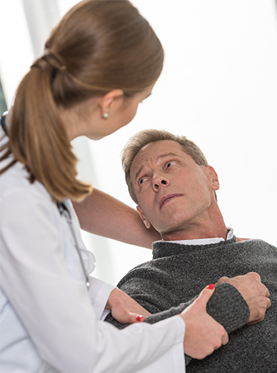 GP examining a concerned male patient’s neck and shoulder during consultation at Mittagong Doctors.