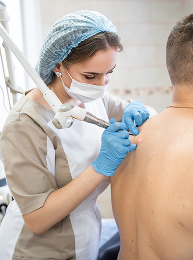 Clinician performing a minor skin procedure with a dermatology device on a patient’s back at Mittagong Doctors.