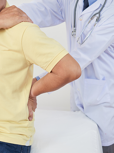 Doctor supporting a patient’s lower back during a pain assessment at Mittagong Doctors.